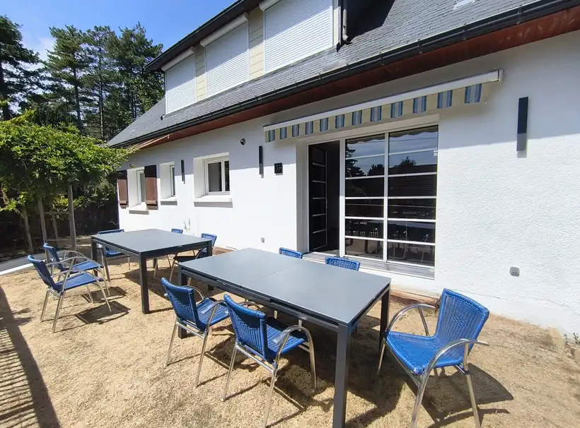 Terrasse de la villa avec deux grandes tables et chaises supplémentaires pour accueillir les groupes